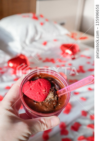 Hand Holding Heart Shaped Dessert with Romantic Bed Decoration Hand Holding Heart Shaped Dessert with Romantic Bed Decoration 135996658
