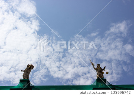 Allegorical statues on historic building roof against sky 135996742