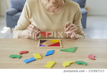 Elderly woman solving geometric puzzle for dementia therapy and brain training 135997317