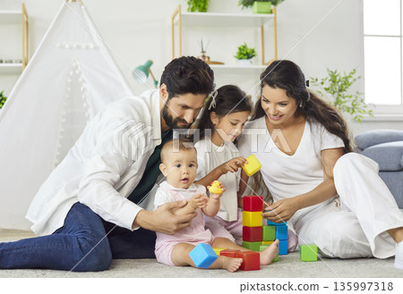 Happy parents and kids playing with colorful building blocks in living room at home 135997318
