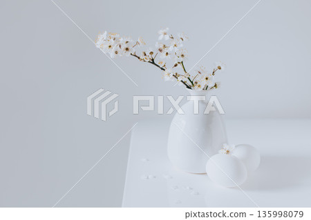 Beautiful blossom branches in a vase and eggs on a white background. Spring minimalistic concept. 135998079