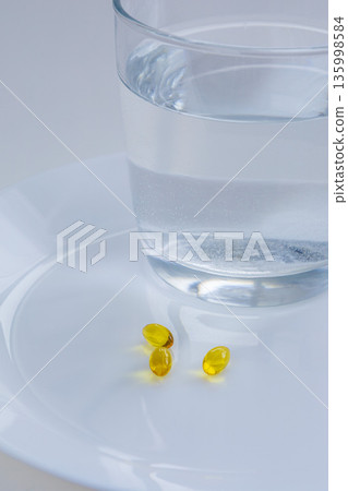 Vitamins and pills with glass of water 135998584