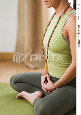 Hispanic woman meditating in yoga half lotus pose ardha padmasana Hispanic woman meditating in yoga half lotus pose ardha padmasana 135998685