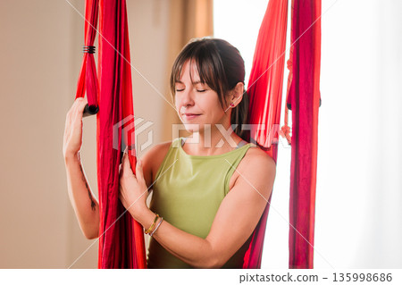 Woman meditating during aerial yoga class Woman meditating during aerial yoga class 135998686
