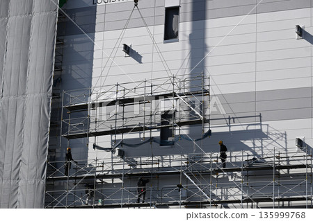 Scaffolding removal work using a crane at a new logistics facility construction site Scaffolding removal work using a crane at a new logistics facility construction site 135999768