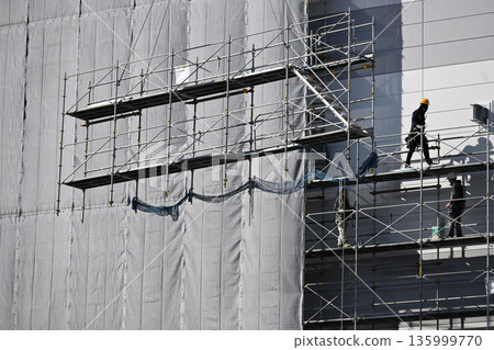 Scaffolding removal work using a crane at a new logistics facility construction site Scaffolding removal work using a crane at a new logistics facility construction site 135999770