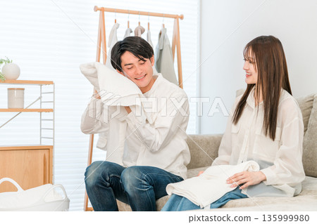 一對面帶微笑的夫婦在客廳裡疊衣服 135999980