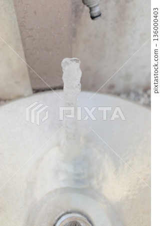 Icicles on a garden faucet and outdoor winter scenery Icicles on a garden faucet and outdoor winter scenery 136000403