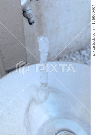 Icicles on a garden faucet and outdoor winter scenery Icicles on a garden faucet and outdoor winter scenery 136000404