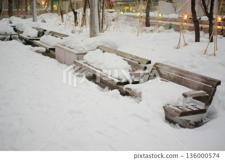Snow-covered park bench and winter cityscape Snow-covered park bench and winter cityscape 136000574