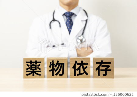 一塊寫著「毒癮」字樣的磚塊，旁邊站著一位醫生 136000625