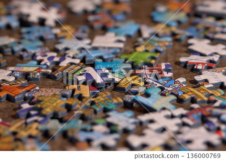 many multicolored jigsaw puzzle pieces spread across a textured surface 136000769