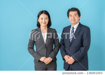Middle-aged male and female businessmen on blue background Middle-aged male and female businessmen on blue background 136001003