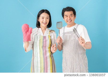 一對中年夫婦在藍色背景前做飯 136001037