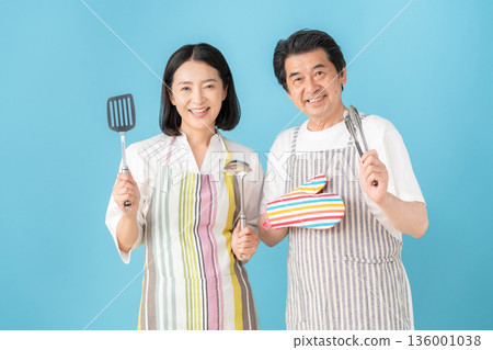 一對中年夫婦在藍色背景前做飯 136001038