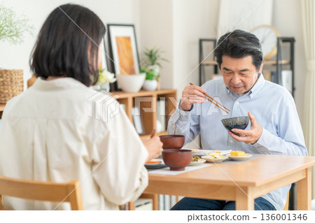 A middle-aged couple having a meal at home 136001346