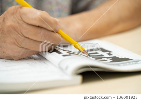 Bangkok, Thailand - May 15, 2022 elderly woman playing sudoku puzzle game. 136001925