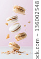 Delicious French Macaroons Floating Above Crumbled Cookies on a Soft Pink Background Capturing the Essence of Gourmet Desserts and Sweet Treats Concept 136002548