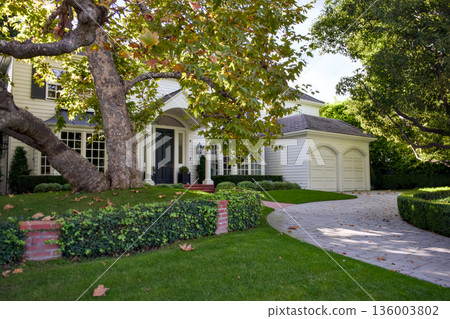 Elegant suburban house with driveway and lush green garden Elegant suburban house with driveway and lush green garden 136003802