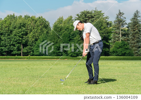 Male golfer playing golf on a golf course (iron shot) Male golfer playing golf on a golf course (iron shot) 136004109