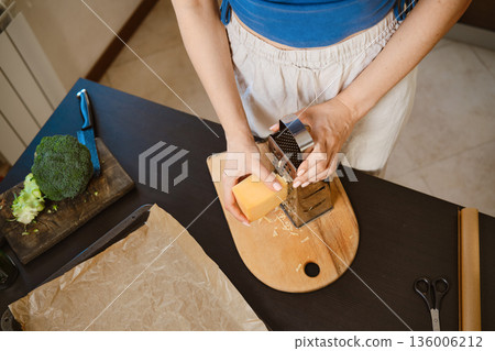 Preparation of smashed broccoli with cheese in a kitchen setting during the daytime Preparation of smashed broccoli with cheese in a kitchen setting during the daytime 136006212