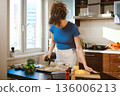 Woman pouring olive oil over the parchment 136006213