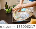 Preparation of smashed broccoli with cheese in a kitchen setting during daytime 136006217
