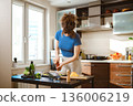 Woman sprinkles pepper over smashed broccoli with cheese in a kitchen during daytime preparation 136006219