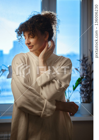 Woman poses near window with natural light in indoor setting during daytime 136006230