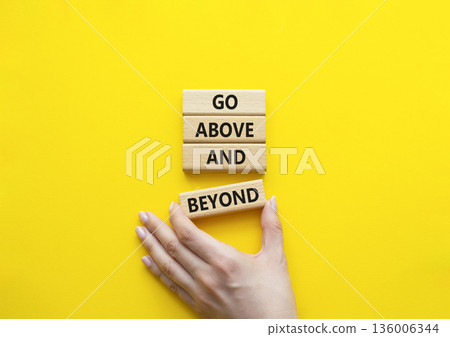 Go above and beyond symbol. Concept words Go above and beyond on wooden blocks. Beautiful bright yellow background. Businessman hand. Business and Go above and beyond concept. Copy space. Go above and beyond symbol. Concept words Go above and beyond on wooden blocks. Beautiful bright yellow background. Businessman hand. Business and Go above and beyond concept. Copy space. 136006344