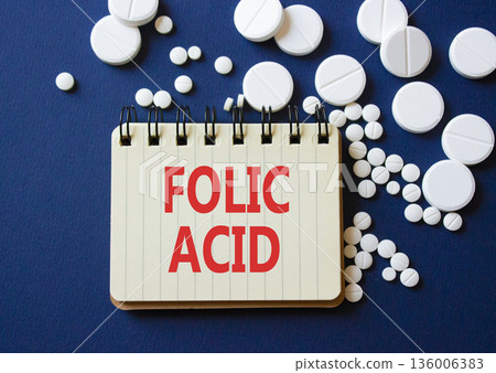 Folic acid symbol. Concept word Folic acid on notebook. Beautiful deep blue background with pills. Medicine and Folic acid concept. Copy space Folic acid symbol. Concept word Folic acid on notebook. Beautiful deep blue background with pills. Medicine and Folic acid concept. Copy space 136006383