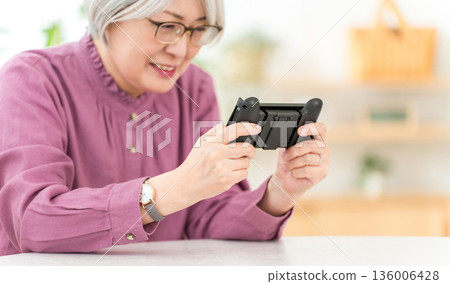 A gray-haired Asian woman playing games in the living room at home A gray-haired Asian woman playing games in the living room at home 136006428