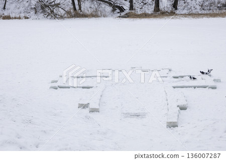 Cross on the river Psel in Sumy in winter. The carved form the shape of a Christian cross, symbol of sacrifice, resurrection, and hope during the Epiphany celebrations the baptism of Jesus Christ. 136007287