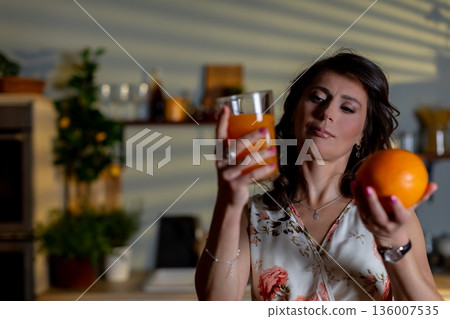 Woman in kitchen evaluates flavors and sensations of fruits and drinks, Caucasian woman meticulously assesses sensory attributes of various fruits and beverages in kitchen setting 136007535