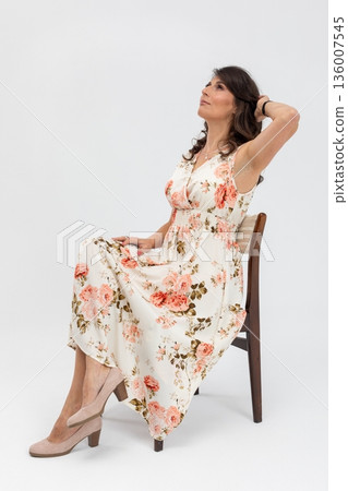Woman relaxing creatively, Relaxed female author sitting in bright creative studio, Casual woman with floral attire resting thoughtfully on wooden chair in vibrant studio Woman relaxing creatively, Relaxed female author sitting in bright creative studio, Casual woman with floral attire resting thoughtfully on wooden chair in vibrant studio 136007545