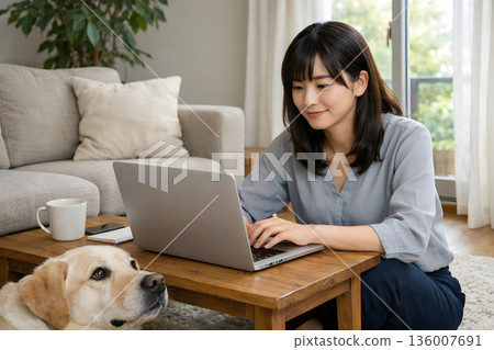 A woman and her dog working in the living room 136007691