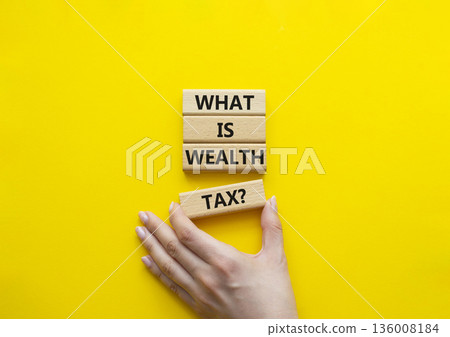 Tax symbol. Concept words What is Wealth Tax on wooden blocks. Beautiful bright yellow background. Businessman hand. Business and What is Wealth Tax concept. Copy space. 136008184