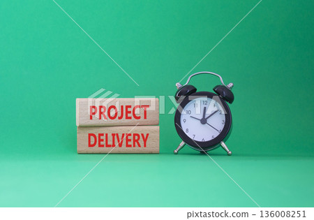 Project Delivery symbol. Concept word Project Delivery on wooden blocks. Beautiful green background with alarm clock. Business and Project Delivery concept. Copy space 136008251