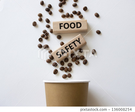Food Safety symbol. Concept words Food Safety on beautiful wooden picture frame. Beautiful white background with coffee cup and coffee beans. Business and Food Safety concept. Copy space. Food Safety symbol. Concept words Food Safety on beautiful wooden picture frame. Beautiful white background with coffee cup and coffee beans. Business and Food Safety concept. Copy space. 136008254