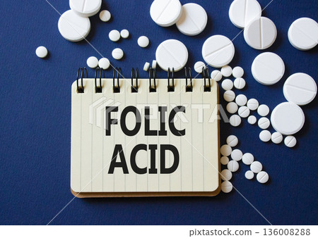 Folic acid symbol. Concept word Folic acid on notebook. Beautiful deep blue background with pills. Medicine and Folic acid concept. Copy space Folic acid symbol. Concept word Folic acid on notebook. Beautiful deep blue background with pills. Medicine and Folic acid concept. Copy space 136008288
