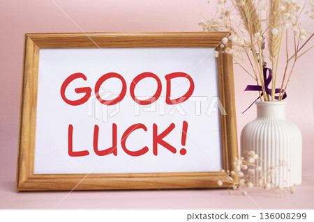 Good luck symbol. Concept words Good luck on beautiful wooden picture frame. Beautiful pink background with flower vase. Business and Good luck concept. Copy space. 136008299