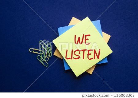 We listen symbol. Yellow sticky note with words We listen. Beautiful deep blue background. Business and We listen concept. Copy space. We listen symbol. Yellow sticky note with words We listen. Beautiful deep blue background. Business and We listen concept. Copy space. 136008302