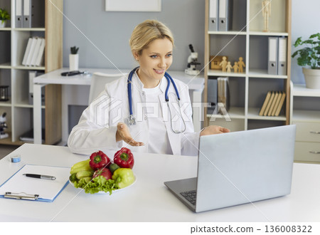 Online dietitian consultation from medical office with laptop and fresh produce Online dietitian consultation from medical office with laptop and fresh produce 136008322
