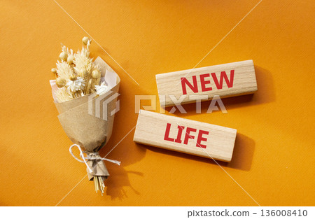 New life symbol. Concept word New life on wooden blocks. Beautiful orange background with bouquet of flowers. Business and New life concept. Copy space New life symbol. Concept word New life on wooden blocks. Beautiful orange background with bouquet of flowers. Business and New life concept. Copy space 136008410