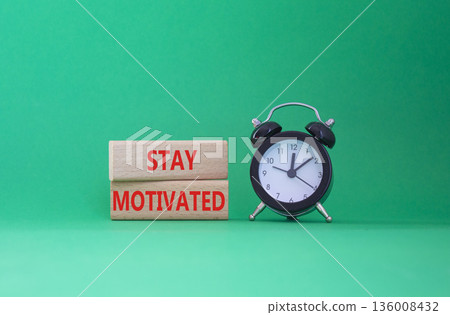 Motivation symbol. Concept words Stay Motivated on wooden blocks. Beautiful green background with alarm clock. Business and Stay Motivated concept. Copy space Motivation symbol. Concept words Stay Motivated on wooden blocks. Beautiful green background with alarm clock. Business and Stay Motivated concept. Copy space 136008432