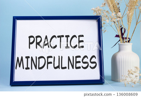 Mindfulness symbol. Concept words Practice Mindfulness on beautiful wooden picture frame. Beautiful light blue background with flower vase. Medical and Psychology concept. Copy space. Mindfulness symbol. Concept words Practice Mindfulness on beautiful wooden picture frame. Beautiful light blue background with flower vase. Medical and Psychology concept. Copy space. 136008609