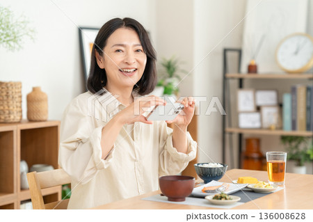 Middle-aged woman eating at home Middle-aged woman eating at home 136008628