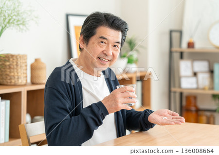Middle-aged man taking supplements at home Middle-aged man taking supplements at home 136008664