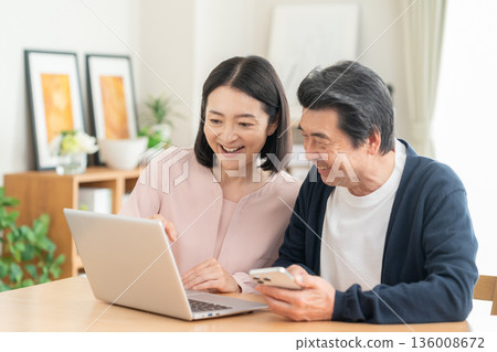 A middle-aged couple watching a smartphone in the living room 136008672