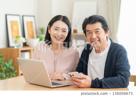 A middle-aged couple watching a smartphone in the living room 136008673